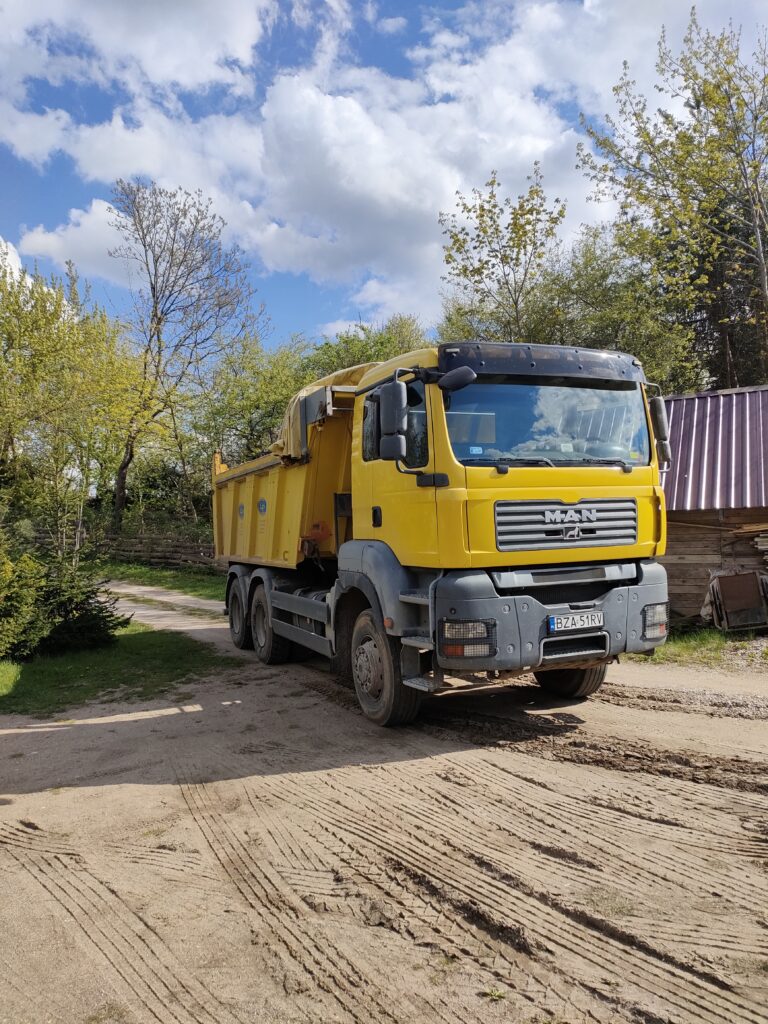 Żółta wywrotka marki MAN na placu budowy, oferowana przez Walenda Usługi Sprzętowe w ramach wynajmu maszyn w Suwałkach i okolicach.